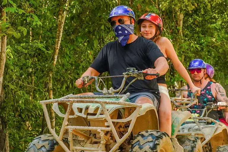 Zwei Teilnehmer fahren gemeinsam auf einem Double-Quad durch den Dschungel der Riviera Maya.