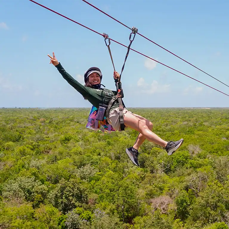 Teilnehmer gleitet bei einem Abenteuer-Ausflug in Mexiko mit einer Zipline über den tropischen Dschungel der Riviera Maya.