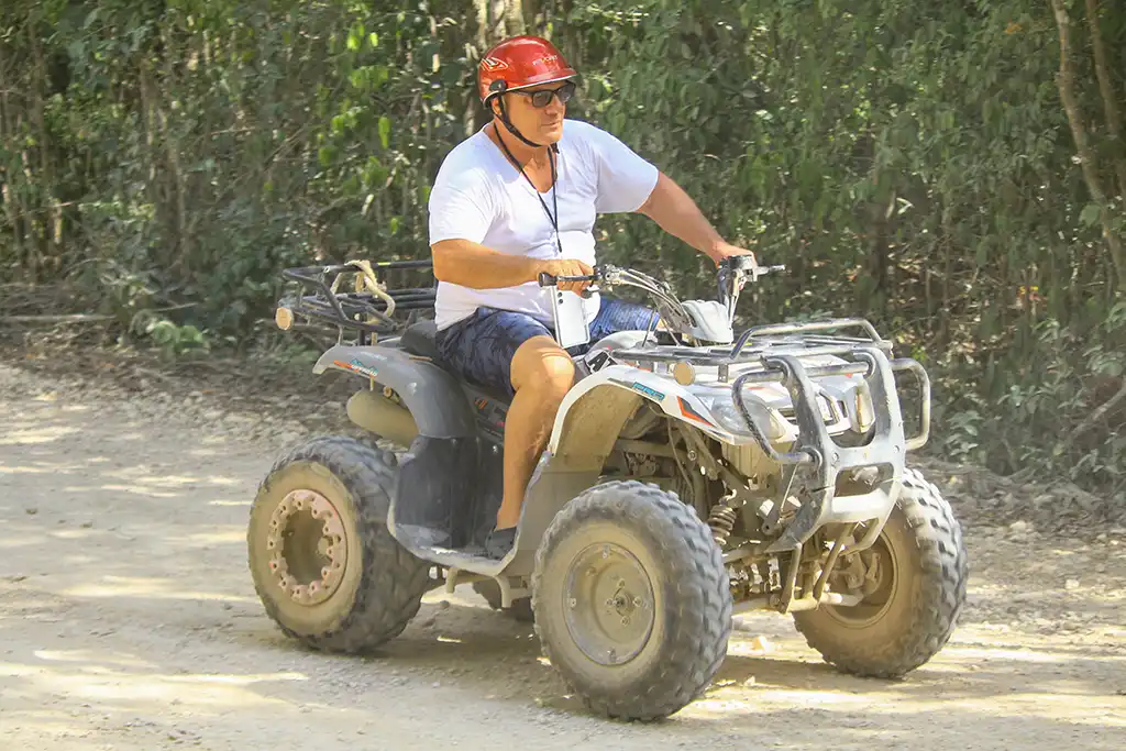 Teilnehmer fährt bei einer Quad-Tour auf einem staubigen Dschungelweg in der Riviera Maya.