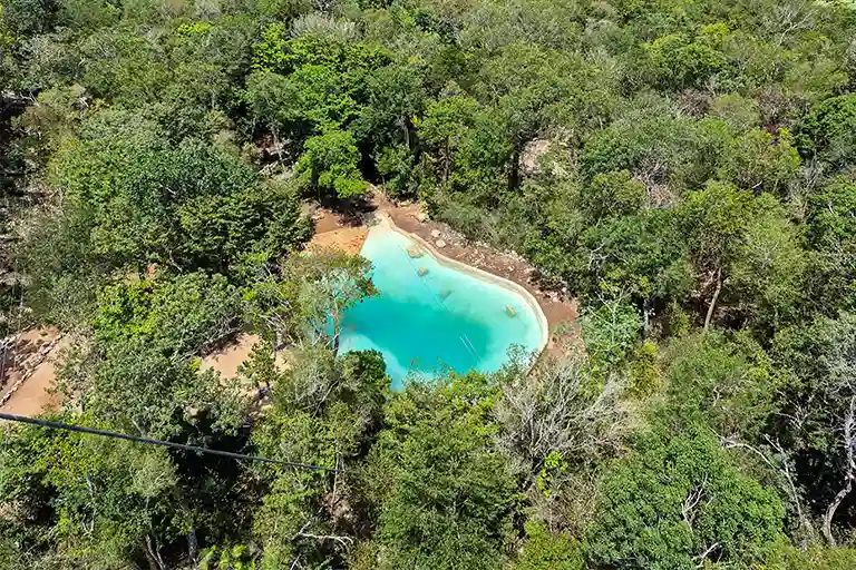 Ausblick von einer Zipline über einen türkisblauen See und den tropischen Dschungel der Riviera Maya.